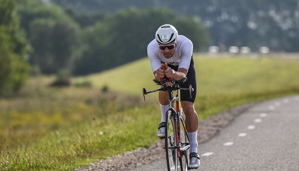 Renner op een tijdritfiets op een landweg langs een groene helling