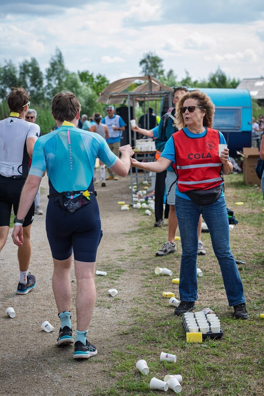 Un bénévole donne un cola à un coureur le long du parcours